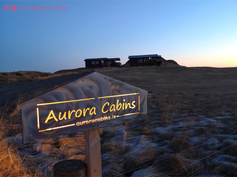El cartel que te da la bienvenida a Aurora Cabins, con las cabañitas al fondo